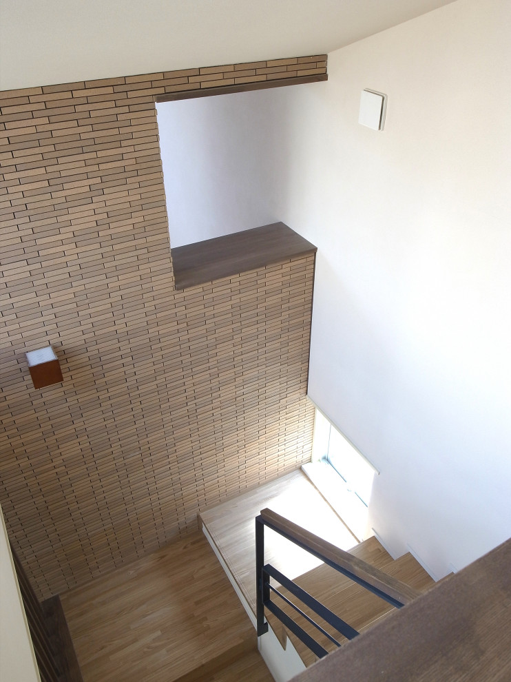 Photo of a modern wood staircase in Tokyo with wood risers, mixed railing and brick walls.