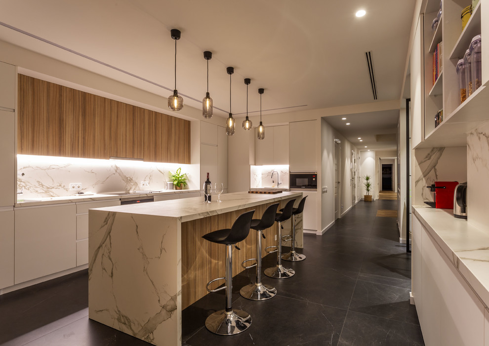 Photo of a contemporary single-wall kitchen in Barcelona with flat-panel cabinets, medium wood cabinets, quartz benchtops, white splashback, with island, white benchtop and black floor.