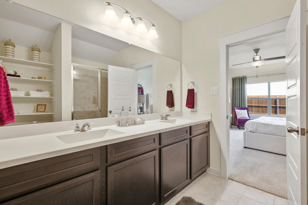 Photo of a transitional master bathroom in Dallas with raised-panel cabinets, dark wood cabinets, an alcove shower, beige tile, ceramic tile, beige walls, ceramic floors, an undermount sink, solid surface benchtops, beige floor, a hinged shower door and white benchtops.