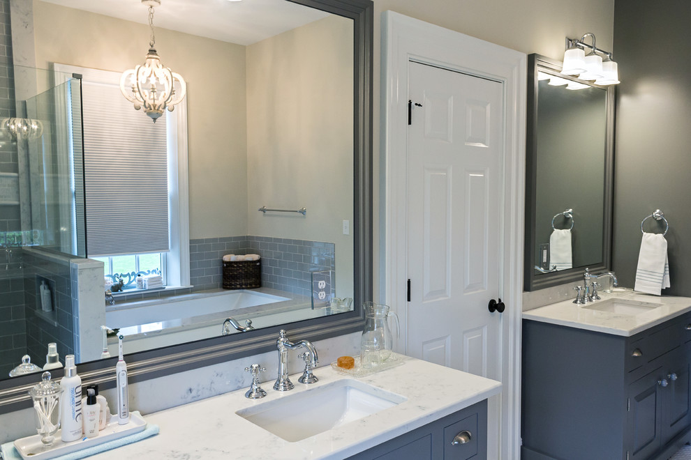 Mid-sized transitional master gray tile and subway tile ceramic tile and white floor corner shower photo with raised-panel cabinets, gray cabinets, an undermount tub, a two-piece toilet, beige walls, an undermount sink, marble countertops and a hinged shower door