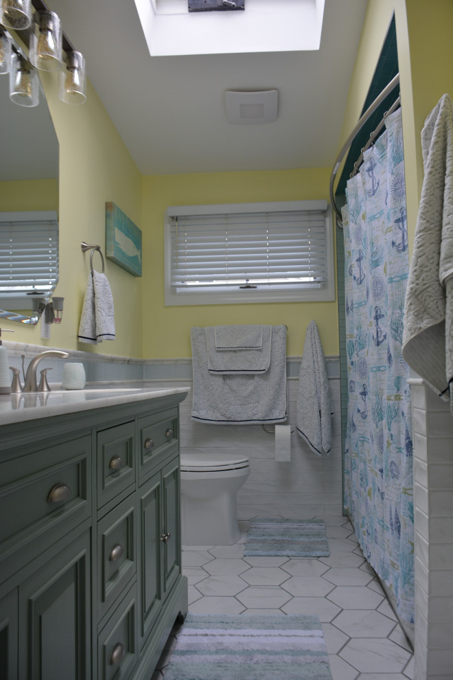 Bathroom - mid-sized coastal kids' white tile and ceramic tile ceramic tile, white floor, double-sink and vaulted ceiling bathroom idea in New York with raised-panel cabinets, green cabinets, a one-piece toilet, yellow walls, an undermount sink, marble countertops, white countertops and a freestanding vanity