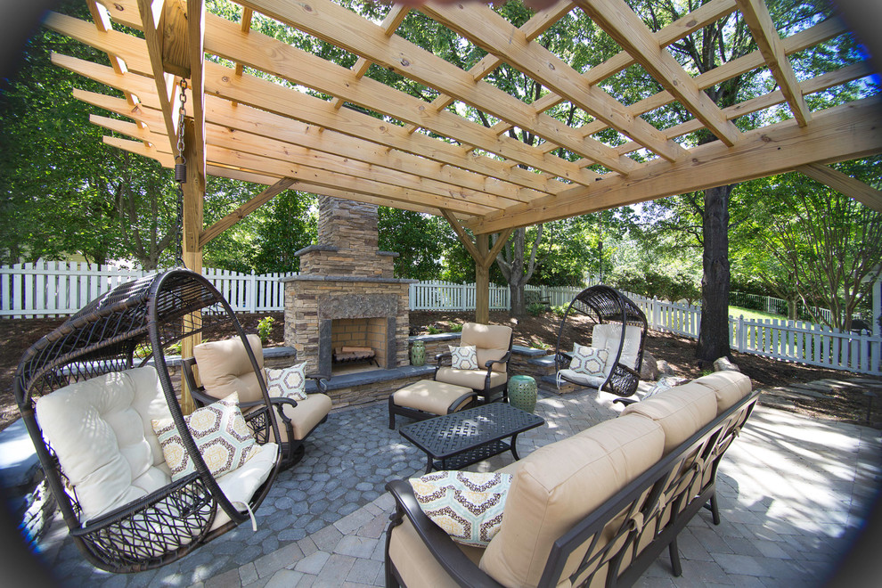 This is an example of a mid-sized contemporary backyard patio in Charlotte with a fire feature, natural stone pavers and a pergola.