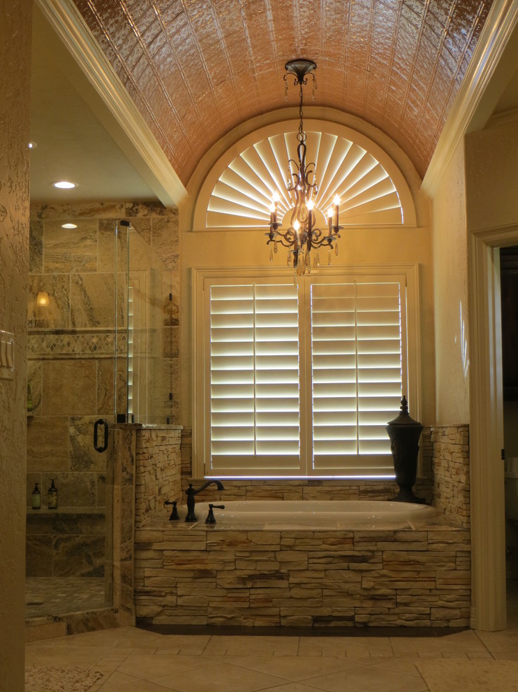 Example of a large mountain style master brown tile and stone tile ceramic tile drop-in bathtub design in Dallas with an undermount sink, raised-panel cabinets, dark wood cabinets, granite countertops, a two-piece toilet and beige walls