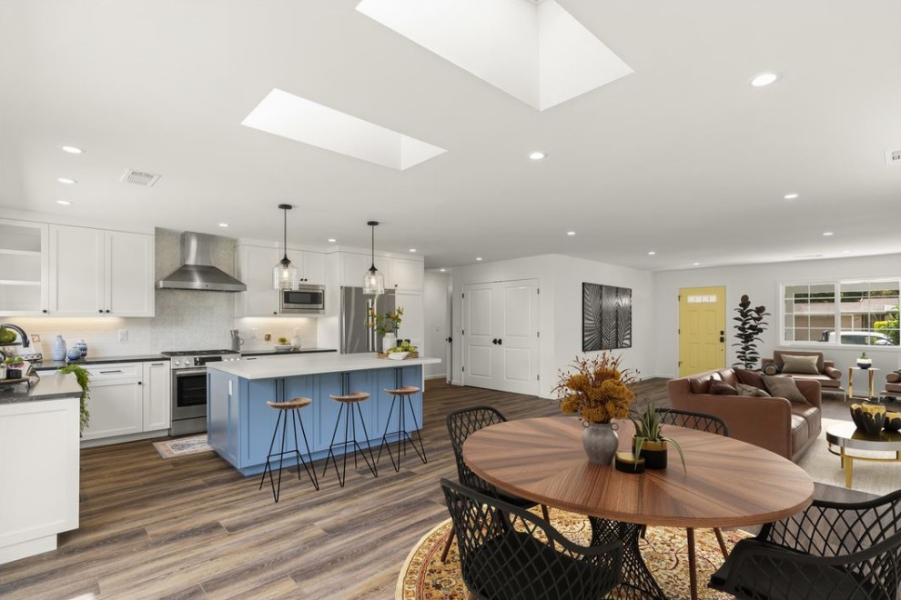 Photo of a large contemporary kitchen/dining room in San Francisco with white walls, vinyl flooring, a standard fireplace, a tiled fireplace surround and brown floors.