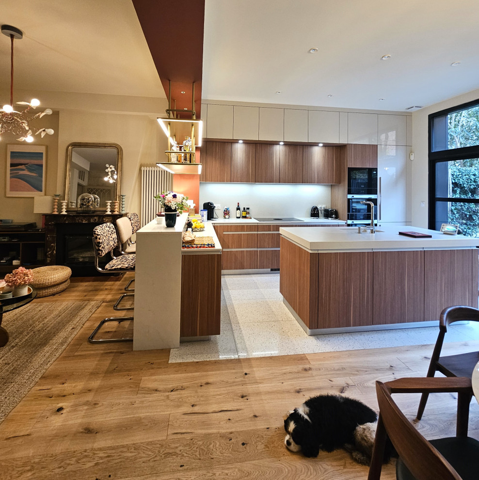 Large midcentury l-shaped seated home bar in Bordeaux with an integrated sink, beaded inset cabinets, medium wood cabinets, quartz benchtops, beige splashback and beige benchtop.