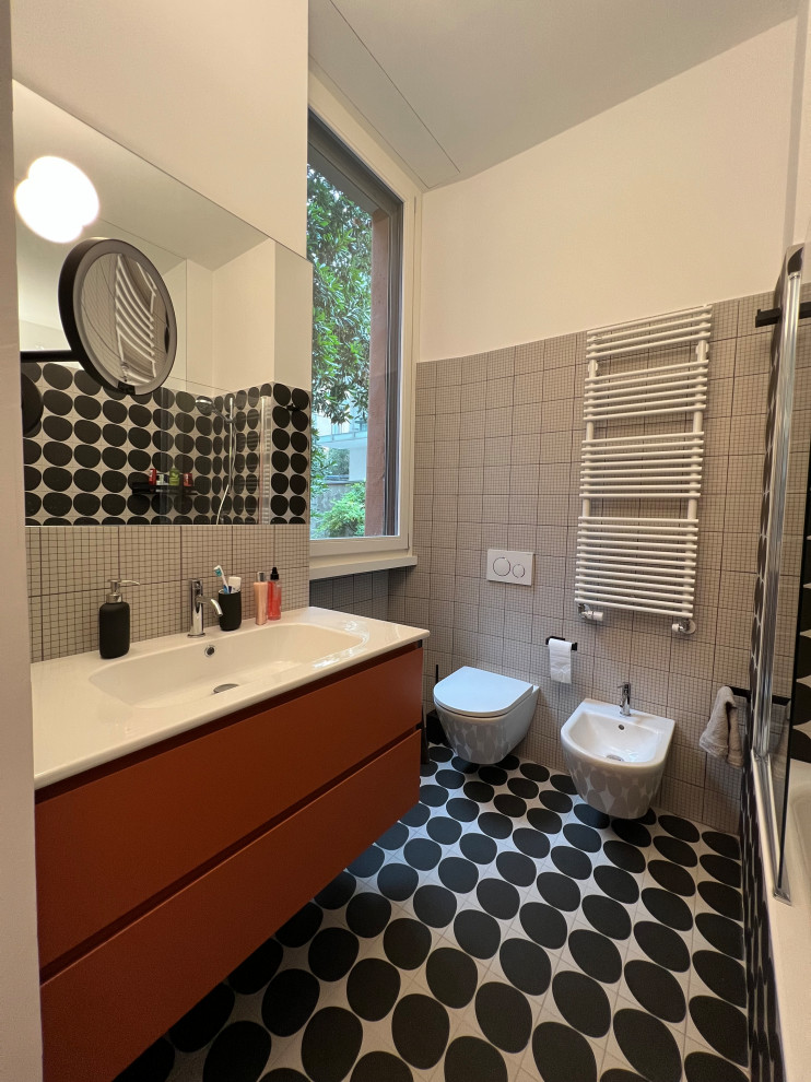 This is an example of a mid-sized modern master bathroom in Milan with orange cabinets, a two-piece toilet, black and white tile, porcelain tile, white walls, porcelain floors, an integrated sink, black floor, white benchtops, a single vanity and a floating vanity.