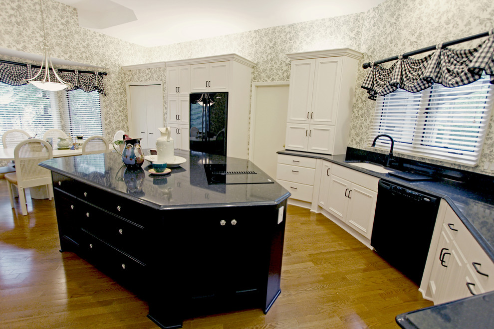 Inspiration for a large traditional u-shaped eat-in kitchen in Cleveland with an undermount sink, raised-panel cabinets, white cabinets, quartz benchtops, black appliances, medium hardwood floors and with island.