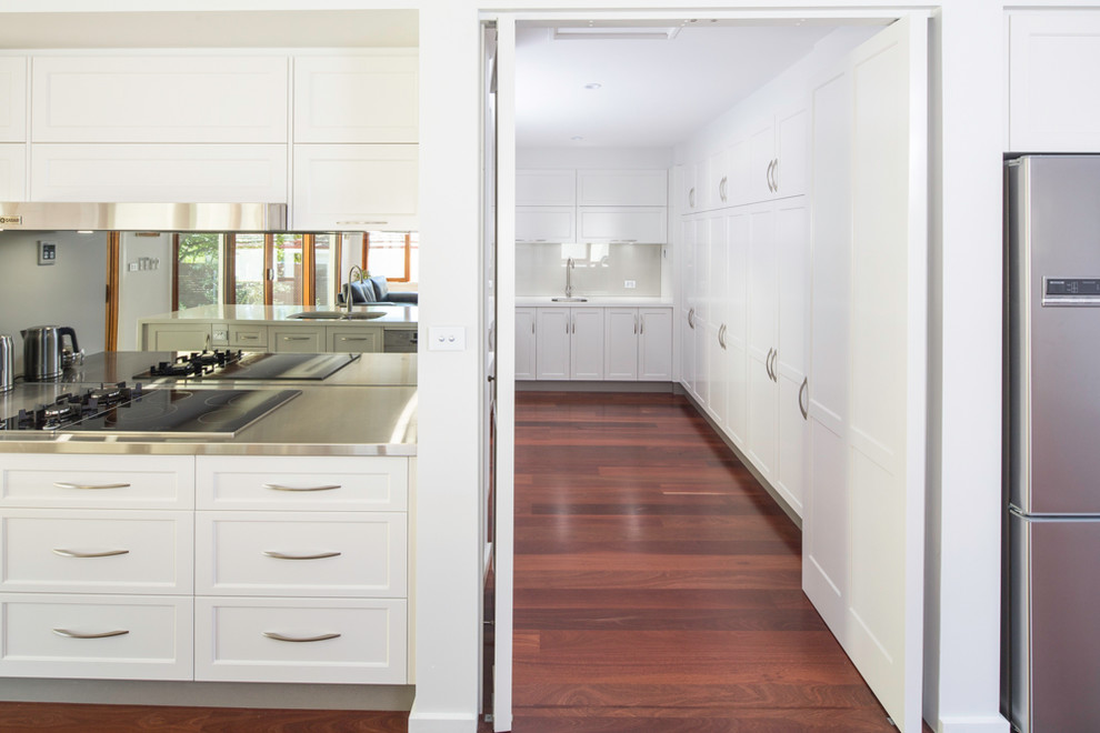 Large traditional galley kitchen pantry in Canberra - Queanbeyan with shaker cabinets, white cabinets, quartz benchtops, glass sheet splashback, dark hardwood floors, with island, an undermount sink, beige splashback, stainless steel appliances and brown floor.