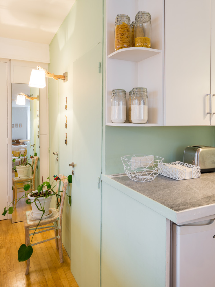 This is an example of a mid-sized scandinavian single-wall open plan kitchen in Lyon with white cabinets, medium hardwood floors, open cabinets and green splashback.