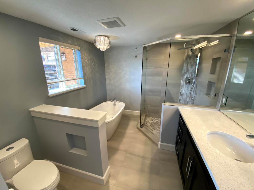 Example of a large transitional single-sink freestanding bathtub design with shaker cabinets, a one-piece toilet, gray walls, an undermount sink, a hinged shower door and a built-in vanity