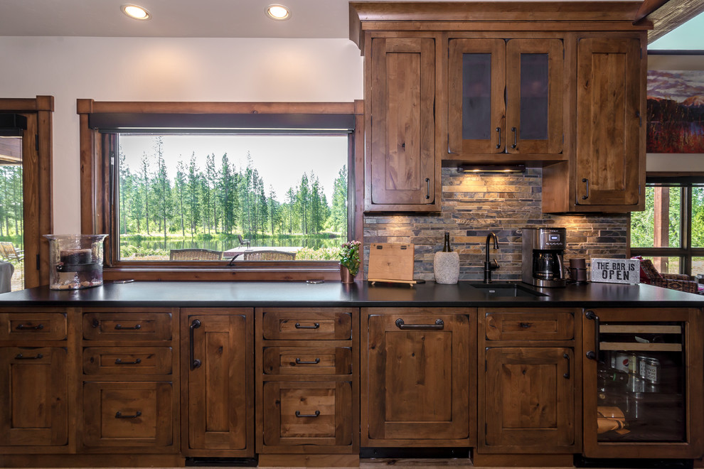Photo of a large country u-shaped open plan kitchen in Denver with a drop-in sink, shaker cabinets, brown cabinets, granite benchtops, stainless steel appliances, medium hardwood floors, with island and brown floor.