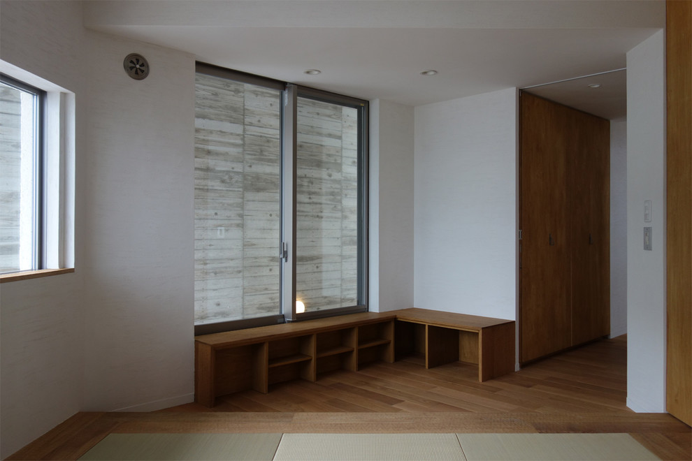 Inspiration pour une chambre d'amis asiatique avec un mur blanc et un sol en bois brun.