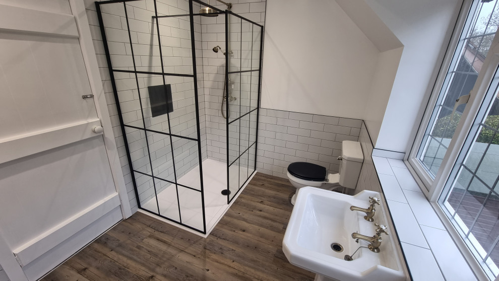 Klassisk inredning av ett stort en-suite badrum, med en öppen dusch, en toalettstol med separat cisternkåpa, vit kakel, keramikplattor, vita väggar, vinylgolv, ett piedestal handfat, flerfärgat golv och med dusch som är öppen