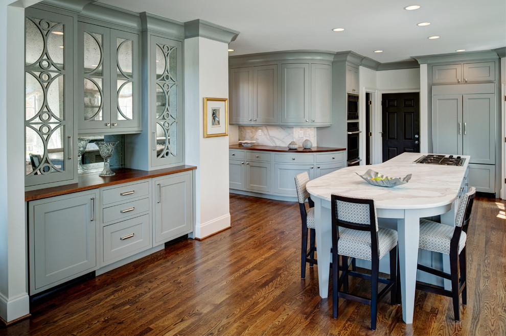 Open concept kitchen - mid-sized transitional l-shaped medium tone wood floor open concept kitchen idea in Atlanta with recessed-panel cabinets, marble countertops, white backsplash, paneled appliances and an island