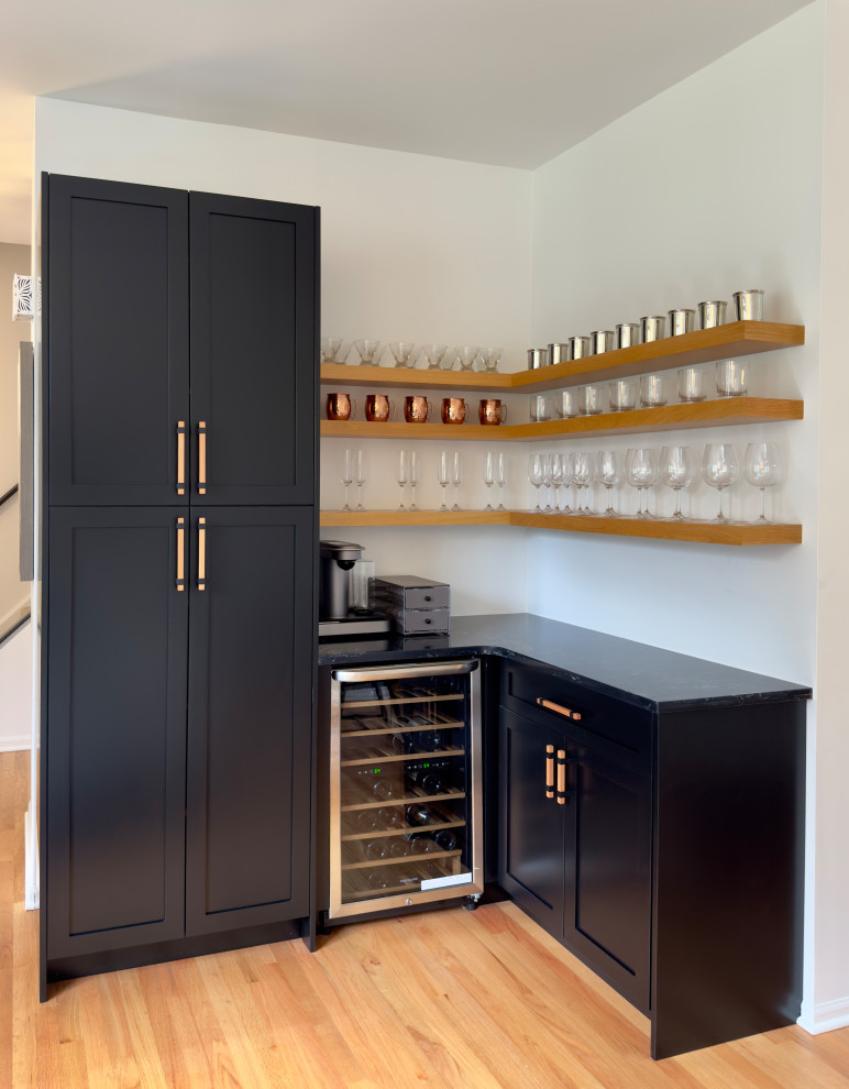 Design ideas for a small contemporary l-shaped dry bar in Chicago with shaker cabinets, black cabinets, engineered stone countertops, light hardwood flooring, orange floors and black worktops.