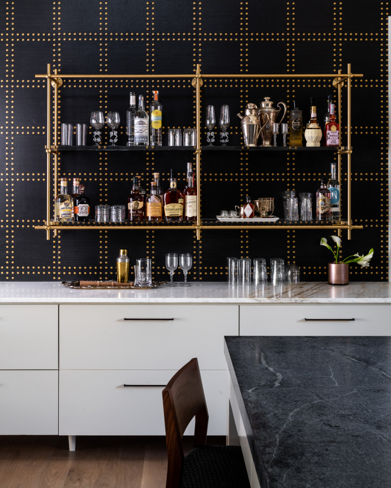 Large transitional single-wall home bar in Dallas with medium hardwood floors, brown floor, an undermount sink, shaker cabinets, medium wood cabinets, soapstone benchtops, white splashback and black benchtop.