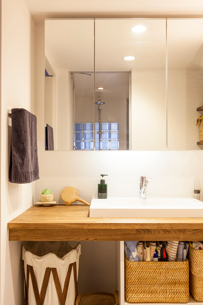 Mid-sized powder room in Tokyo with open cabinets, white cabinets, white walls, a drop-in sink and wood benchtops.