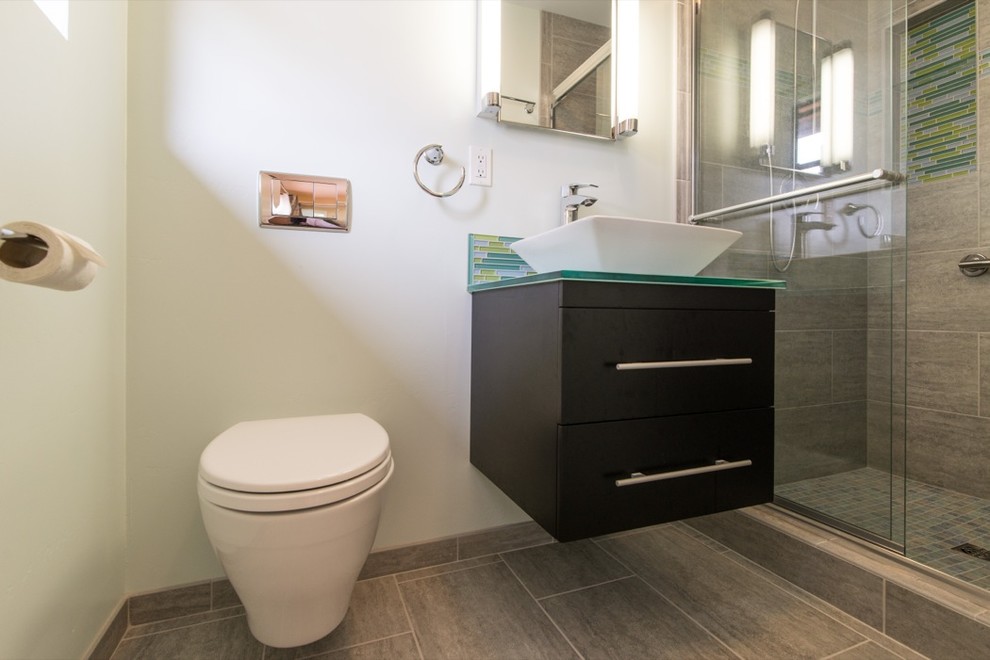 Design ideas for a mid-sized modern bathroom in San Diego with a pedestal sink, dark wood cabinets, glass benchtops, an open shower, a one-piece toilet, multi-coloured tile, glass tile, white walls and porcelain floors.