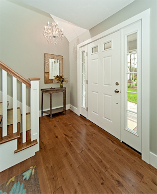 Medium tone wood floor single front door photo in Boston with beige walls and a white front door