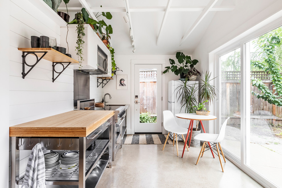 Inspiration for a small beach style galley eat-in kitchen in Portland with wood benchtops, white splashback, timber splashback, concrete floors, stainless steel appliances and grey floor.