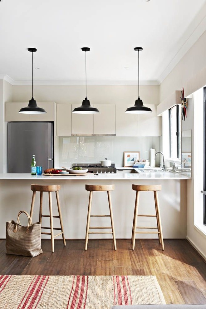 Inspiration for a mid-sized contemporary u-shaped eat-in kitchen in Melbourne with a double-bowl sink, flat-panel cabinets, white cabinets, laminate benchtops, grey splashback, glass sheet splashback, stainless steel appliances, medium hardwood floors and no island.
