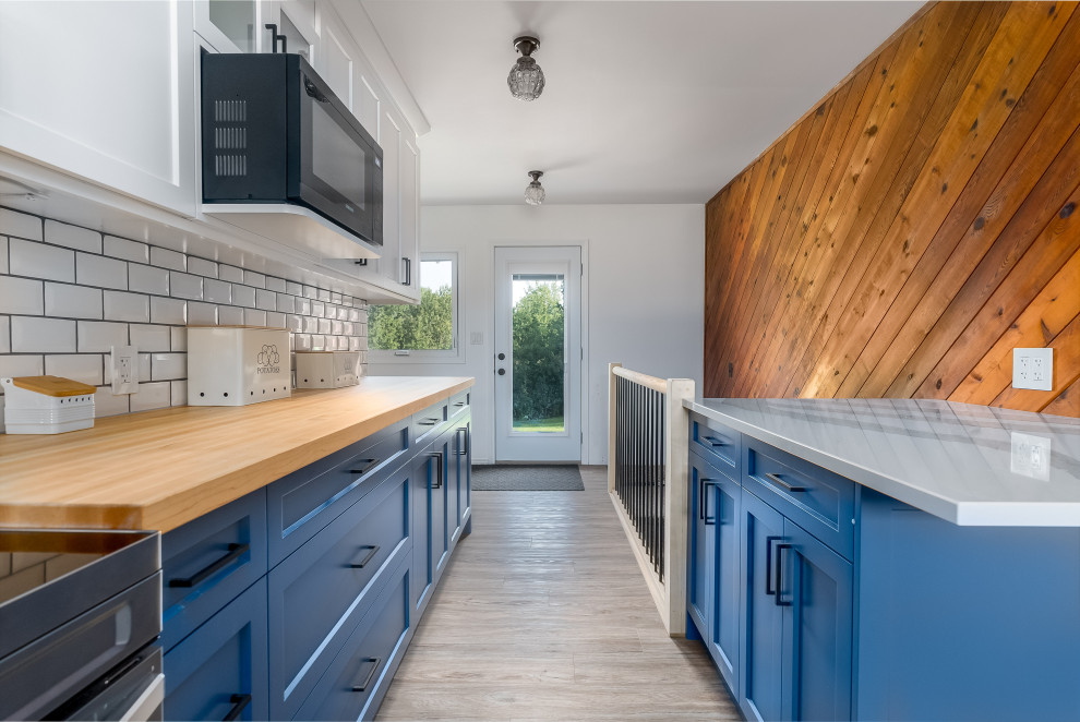 Transitional kitchen photo in Edmonton with shaker cabinets, blue cabinets, quartzite countertops, subway tile backsplash, stainless steel appliances, an island and white countertops