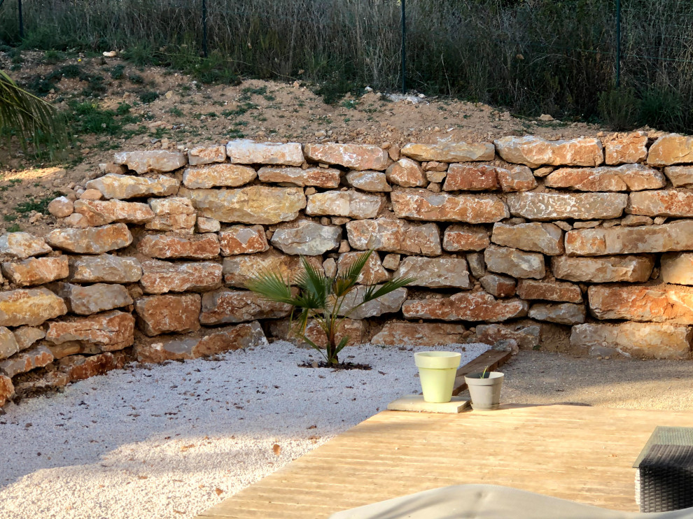 Foto di un grande giardino tradizionale con un muro di contenimento, un pendio, una collina o una riva e recinzione in pietra