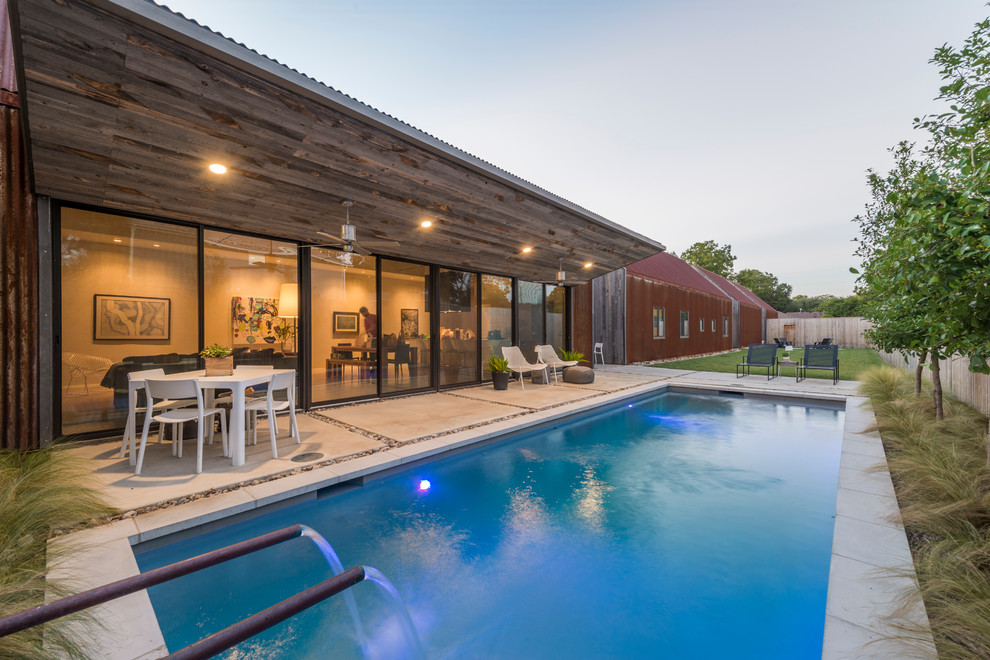 Photo of a small industrial backyard rectangular lap pool in Dallas with concrete slab and a water feature.