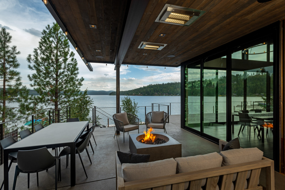 Photo of a contemporary side yard patio in Seattle with a fire feature and a roof extension.