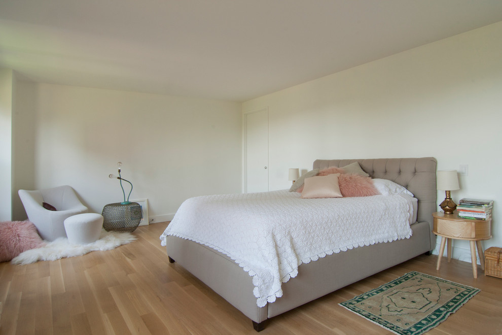 Large contemporary master bedroom in New York with light hardwood floors, beige floor and no fireplace.