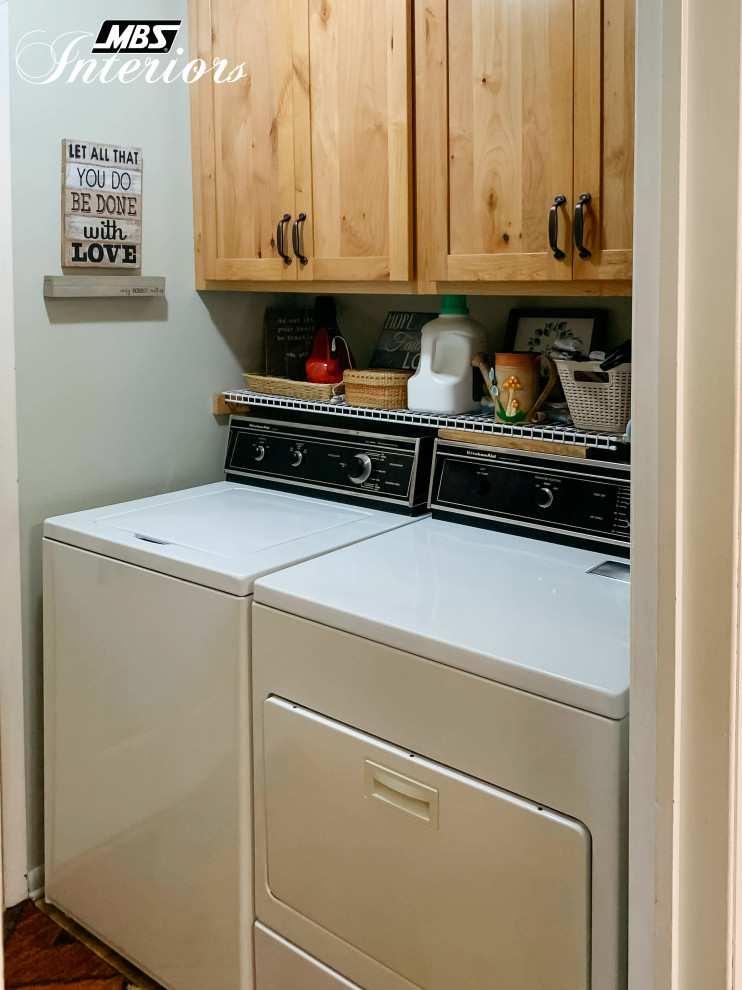 Photo of a small country galley laundry cupboard in Other with shaker cabinets, light wood cabinets, grey walls, light hardwood floors, a side-by-side washer and dryer and beige floor.