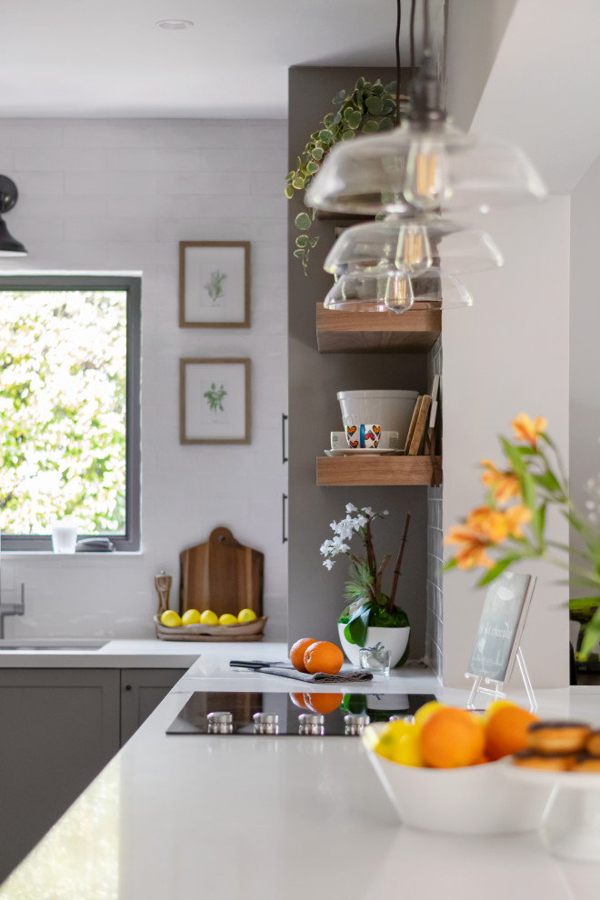 Inspiration for a mid-sized transitional galley medium tone wood floor eat-in kitchen remodel in Miami with an undermount sink, shaker cabinets, gray cabinets, quartz countertops, white backsplash, subway tile backsplash, stainless steel appliances, a peninsula and white countertops