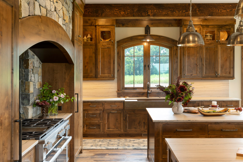 Huge mountain style galley medium tone wood floor, multicolored floor and exposed beam eat-in kitchen photo in Minneapolis with a farmhouse sink, recessed-panel cabinets, distressed cabinets, quartz countertops, multicolored backsplash, quartz backsplash, paneled appliances, two islands and multicolored countertops