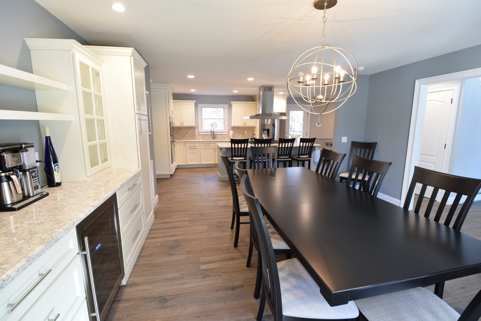 Open concept kitchen - large transitional medium tone wood floor open concept kitchen idea with an undermount sink, beaded inset cabinets, white cabinets, granite countertops, beige backsplash, ceramic backsplash, stainless steel appliances and an island
