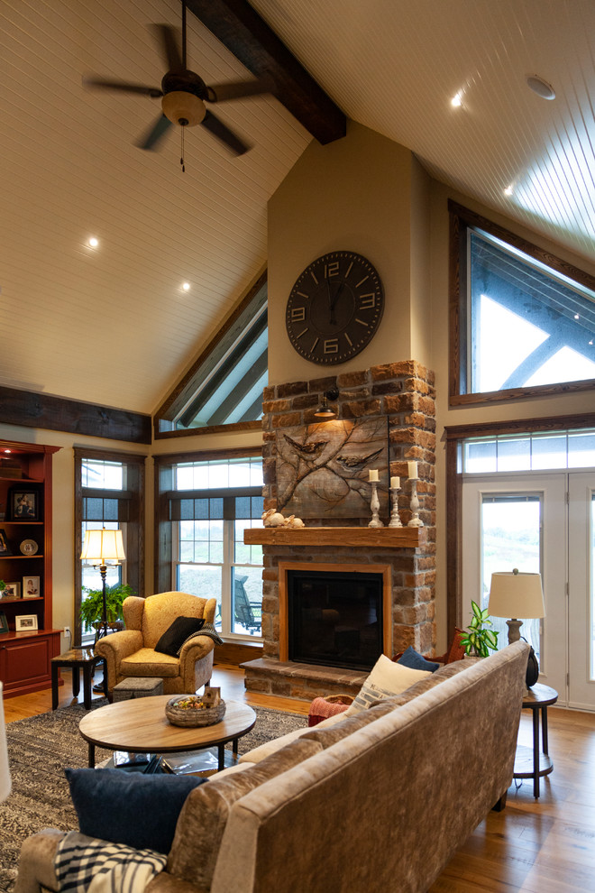 Photo of a mid-sized country open concept living room in Toronto with beige walls, light hardwood floors, a standard fireplace, a brick fireplace surround and a built-in media wall.