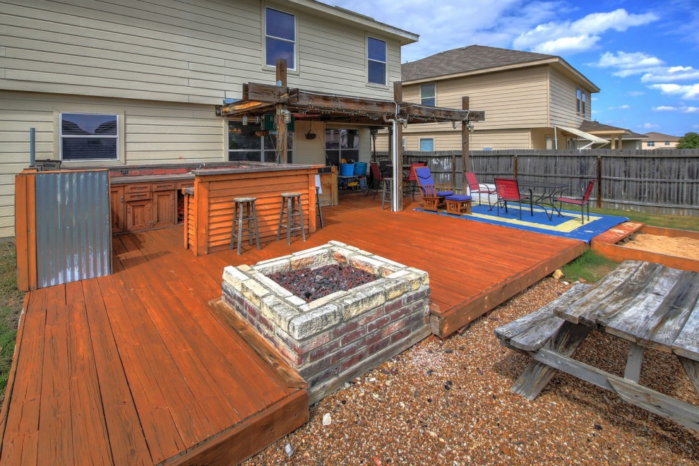 This is an example of a large traditional backyard deck in Austin with a fire feature and a pergola.