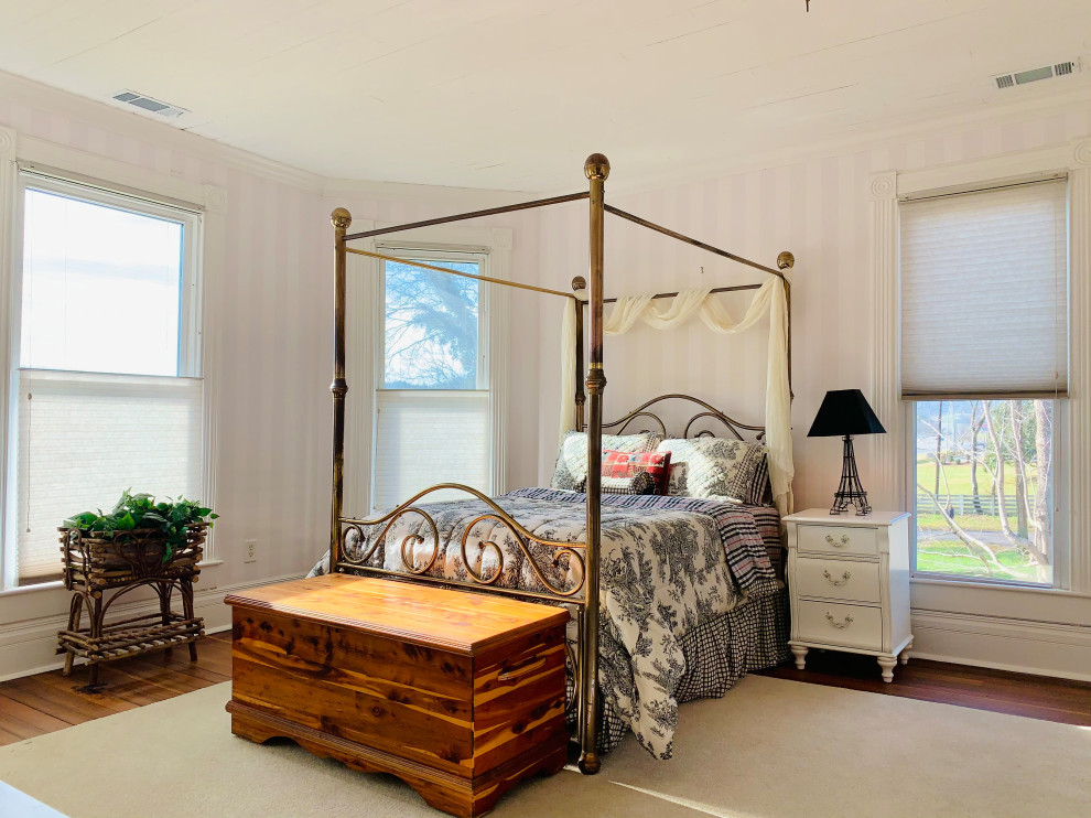 ナッシュビルにある中くらいなヴィクトリアン調のおしゃれな客用寝室 (ピンクの壁、濃色無垢フローリング、標準型暖炉、木材の暖炉まわり、茶色い床、板張り天井、壁紙) のインテリア