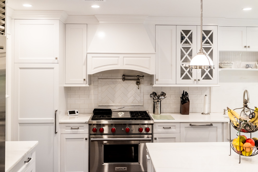 Inspiration for a mid-sized transitional dark wood floor and brown floor enclosed kitchen remodel in New York with a farmhouse sink, recessed-panel cabinets, white cabinets, quartzite countertops, white backsplash, subway tile backsplash, stainless steel appliances and an island