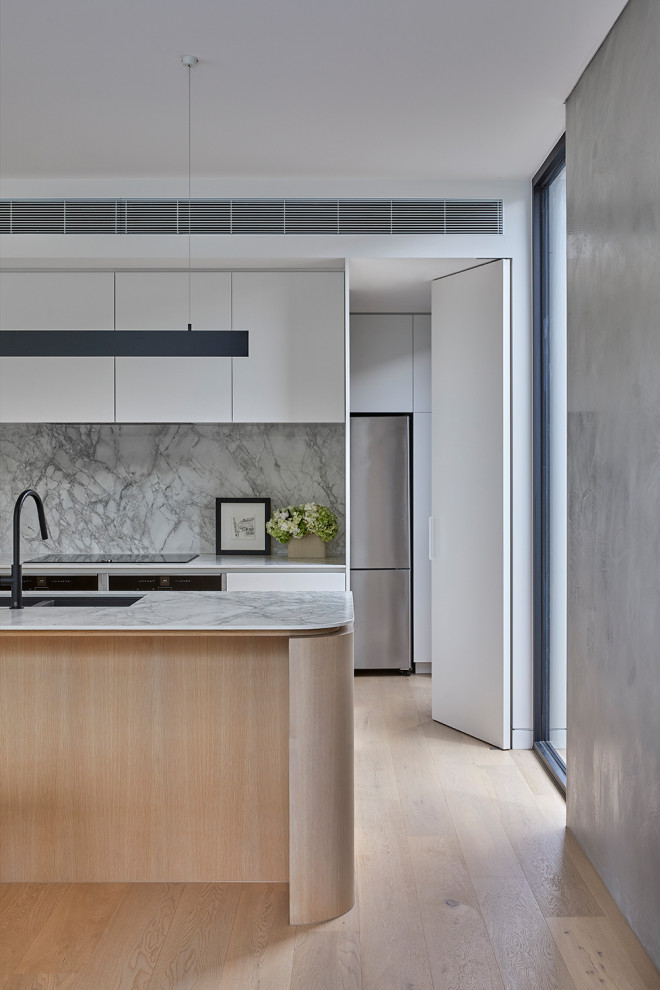 Design ideas for a mid-sized modern galley open plan kitchen in Melbourne with an undermount sink, white cabinets, marble benchtops, white splashback, marble splashback, black appliances, with island and white benchtop.