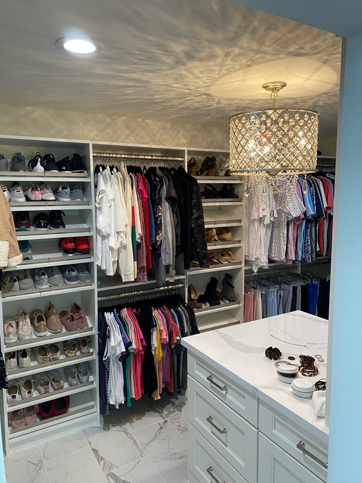 Modelo de armario vestidor de mujer romántico grande con armarios estilo shaker, puertas de armario blancas, suelo de baldosas de porcelana y suelo blanco