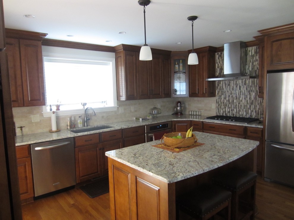 Inspiration for a large transitional l-shaped dark wood floor and brown floor enclosed kitchen remodel with an undermount sink, raised-panel cabinets, granite countertops, an island, dark wood cabinets, beige backsplash, stone tile backsplash and stainless steel appliances
