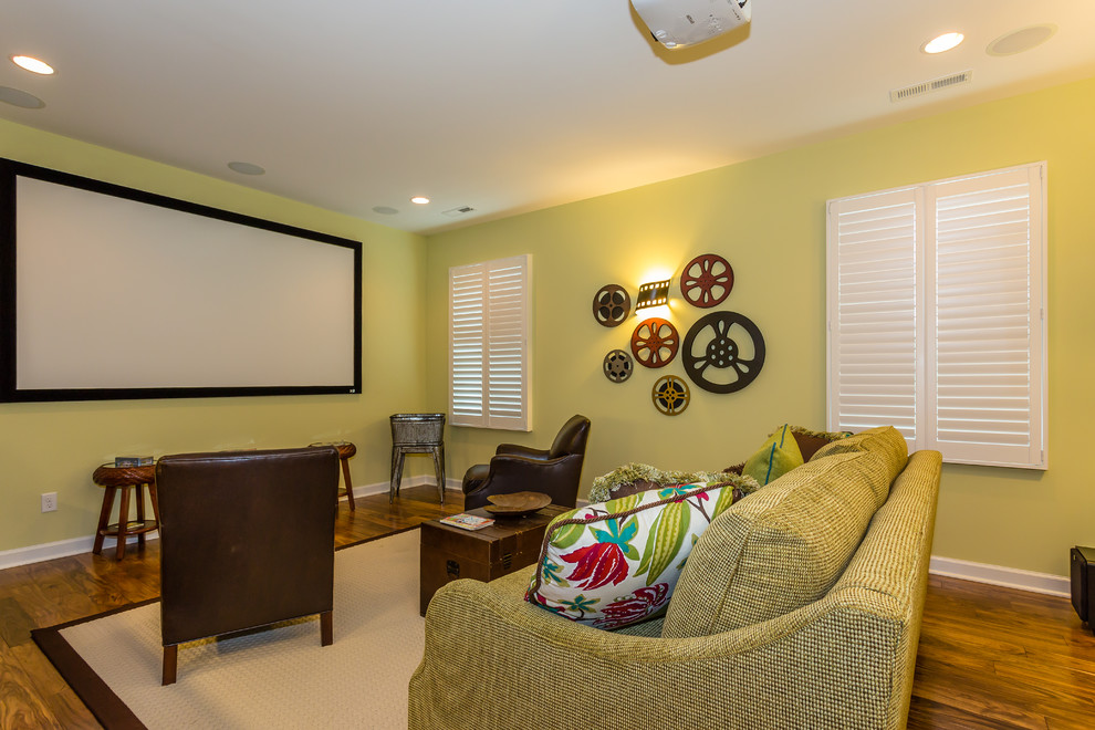 This is an example of a traditional home theatre in Other with green walls, medium hardwood floors and a projector screen.