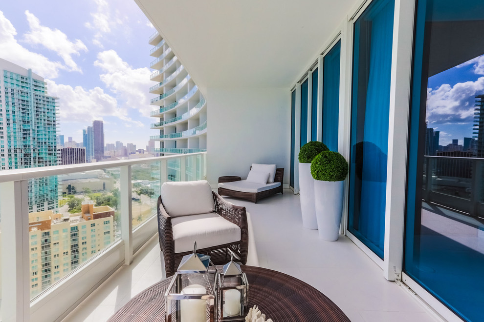 This is an example of a mid-sized contemporary balcony in Miami with a roof extension.