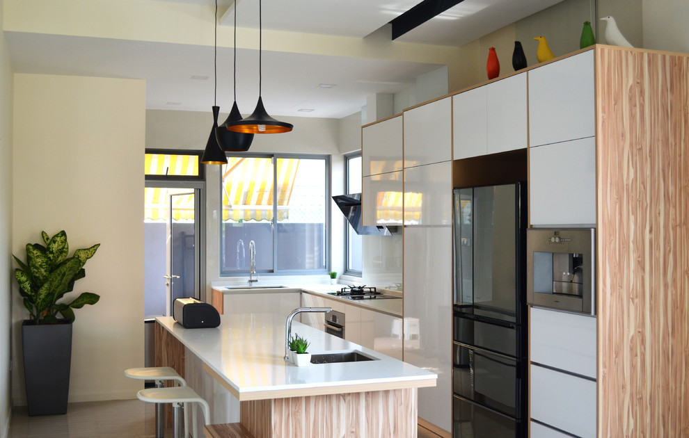 Inspiration for a contemporary l-shaped kitchen in Singapore with an undermount sink, flat-panel cabinets, white cabinets, white splashback, glass sheet splashback, black appliances and with island.
