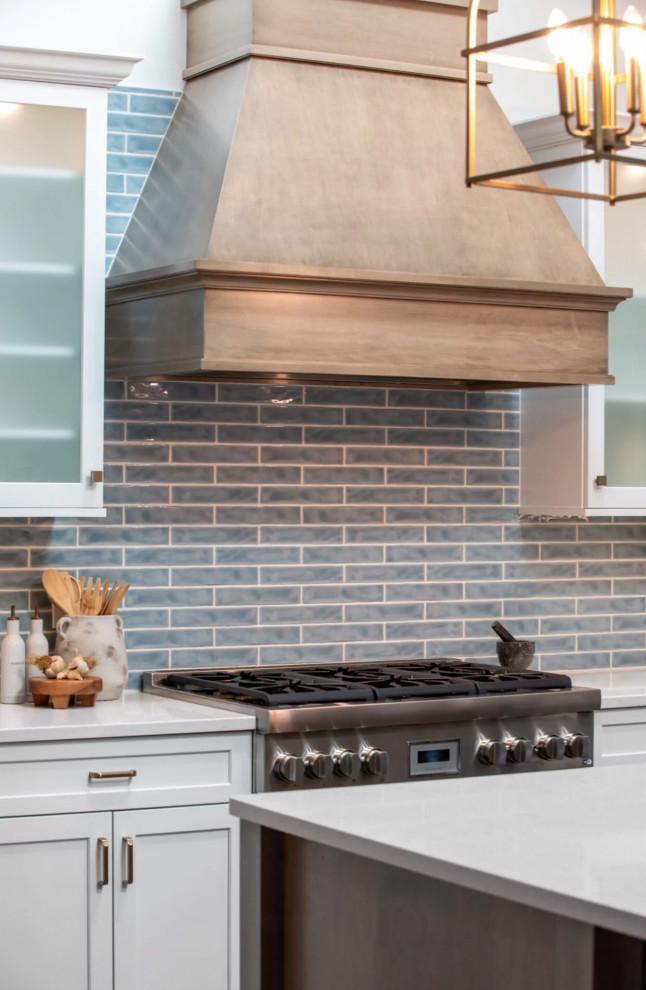 Eat-in kitchen - coastal brown floor and exposed beam eat-in kitchen idea with a farmhouse sink, blue backsplash, porcelain backsplash, stainless steel appliances, an island and white countertops