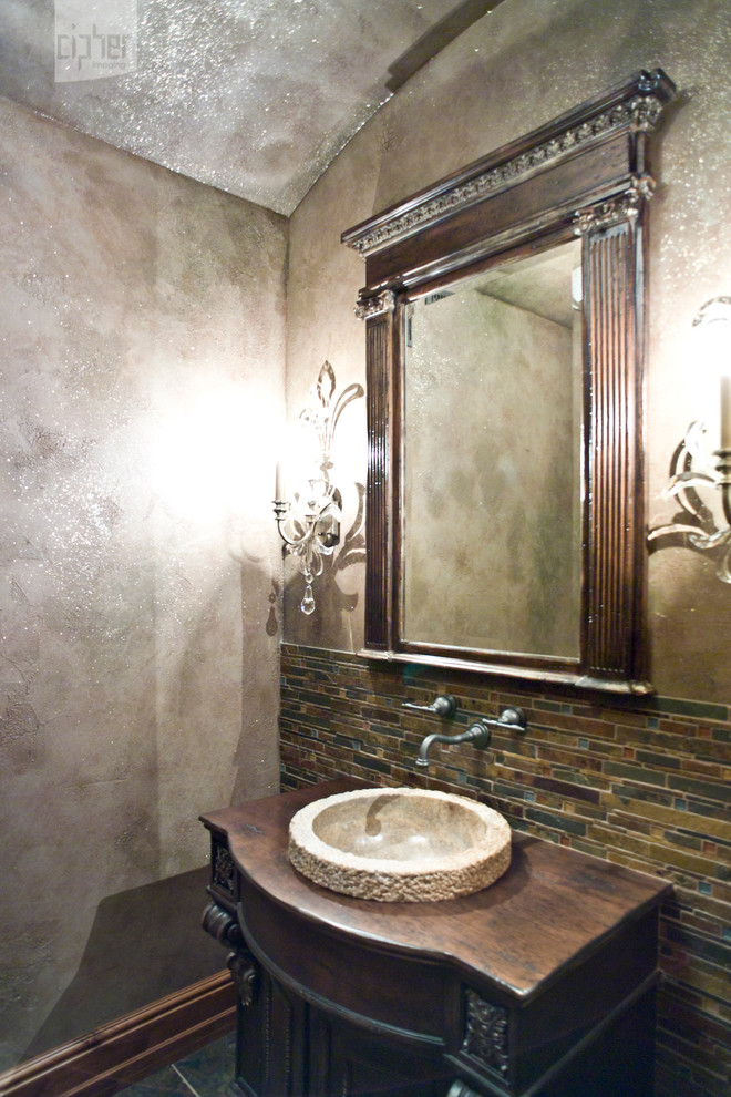 This is an example of a mid-sized country powder room in Other with furniture-like cabinets, dark wood cabinets, multi-coloured tile, mosaic tile, multi-coloured walls, porcelain floors, a vessel sink, wood benchtops and grey floor.