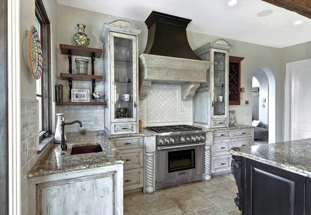 Photo of a large l-shaped separate kitchen in Charleston with an undermount sink, distressed cabinets, white splashback, subway tile splashback, stainless steel appliances, raised-panel cabinets, with island, granite benchtops, grey floor and grey benchtop.