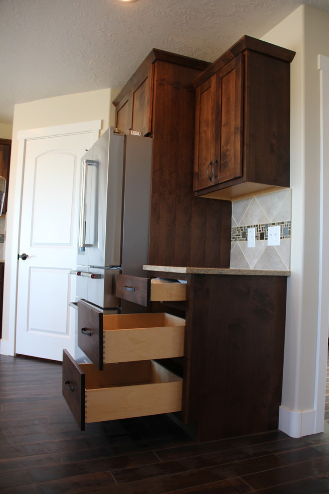 Inspiration for a rustic dark wood floor home design remodel with shaker cabinets, dark wood cabinets, beige backsplash, stainless steel appliances and an island