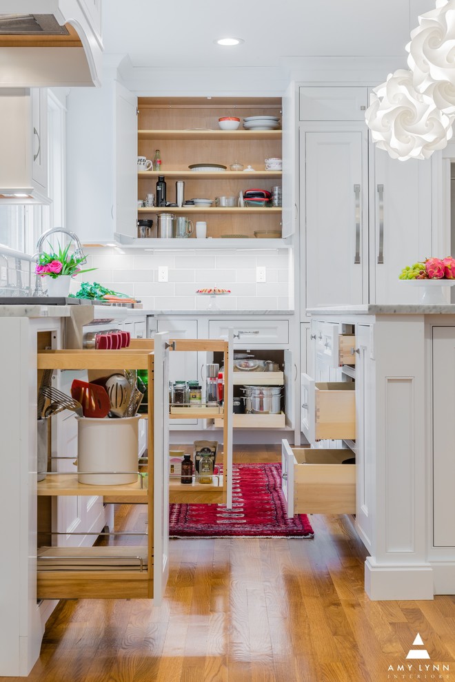 Mid-sized transitional l-shaped medium tone wood floor and red floor eat-in kitchen photo in Boston with an undermount sink, beaded inset cabinets, white cabinets, marble countertops, gray backsplash, porcelain backsplash, paneled appliances, an island and yellow countertops