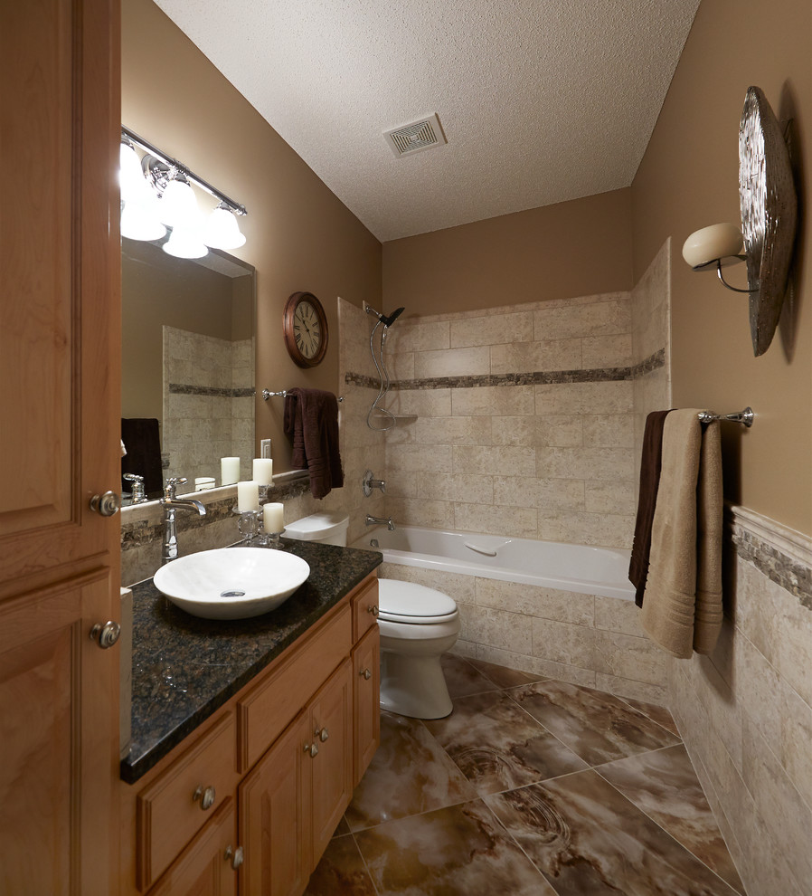 Photo of a mid-sized traditional master bathroom in Minneapolis with raised-panel cabinets, light wood cabinets, a shower/bathtub combo, a one-piece toilet, beige tile, ceramic tile, beige walls, ceramic floors and a vessel sink.